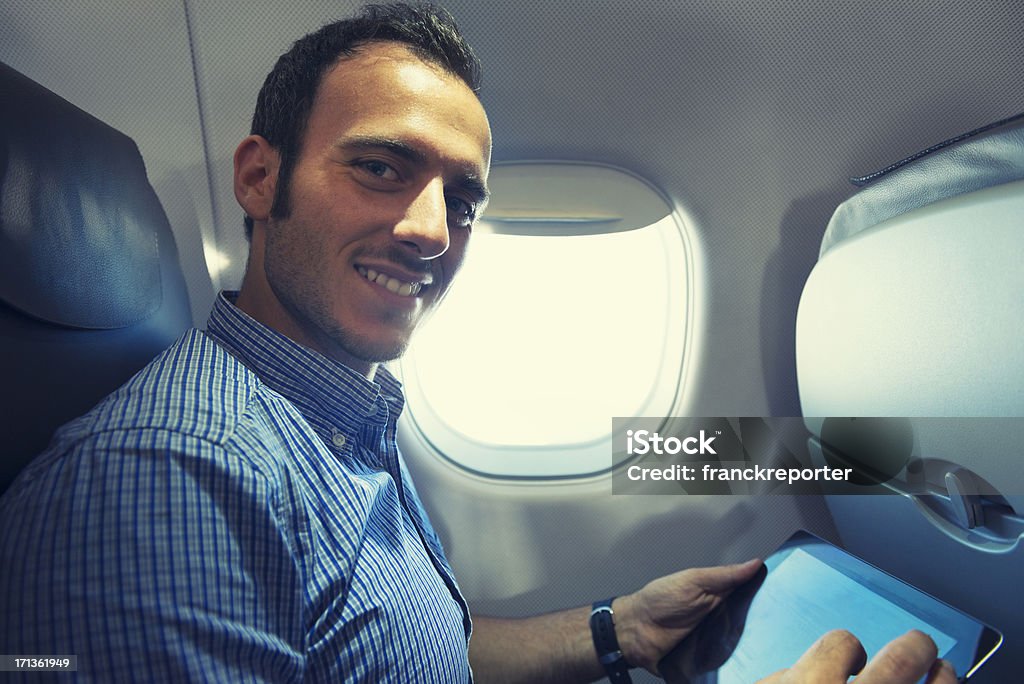 Hombre de negocios usando una tableta digital en el avión - Foto de stock de 25-29 años libre de derechos