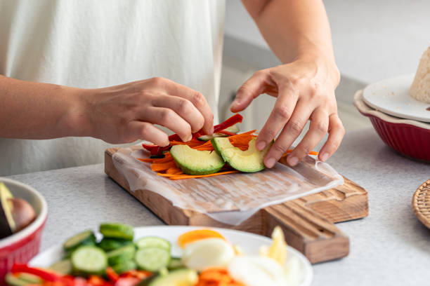 istock Woman preparing spring rolls in rice paper on kitchen table. 1713619791
