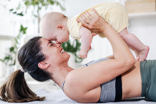 Side view of a mother and her baby girl playing while doing home workout