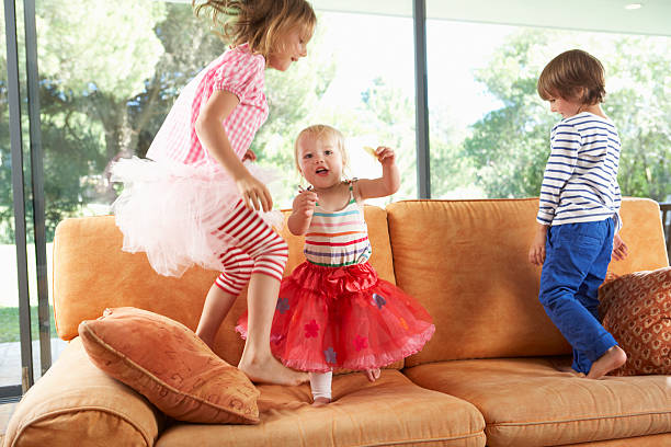 のお子様のグループに飛びついソファー - domestic life jumping child sofa ストックフォトと画像