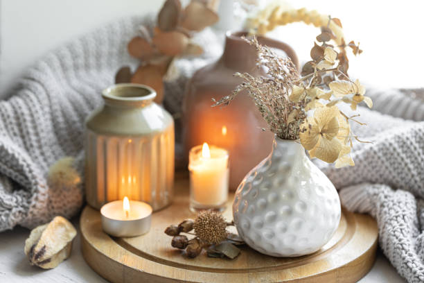 A cozy composition with candles, dried flowers in a vase and a knitted element.