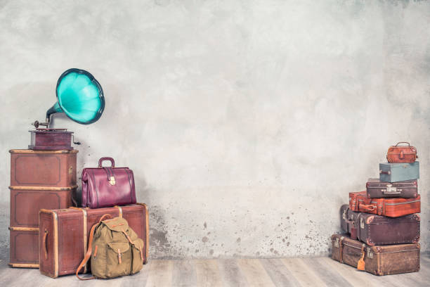 Vintage outdated trunks luggage, old antique leather suitcases pile and classic gramophone front concrete wall background. Travel baggage concept. Retro style filtered photo Vintage outdated trunks luggage, old antique leather suitcases pile and classic gramophone front concrete wall background. Travel baggage concept. Retro style filtered photography old luggage tag stock pictures, royalty-free photos & images