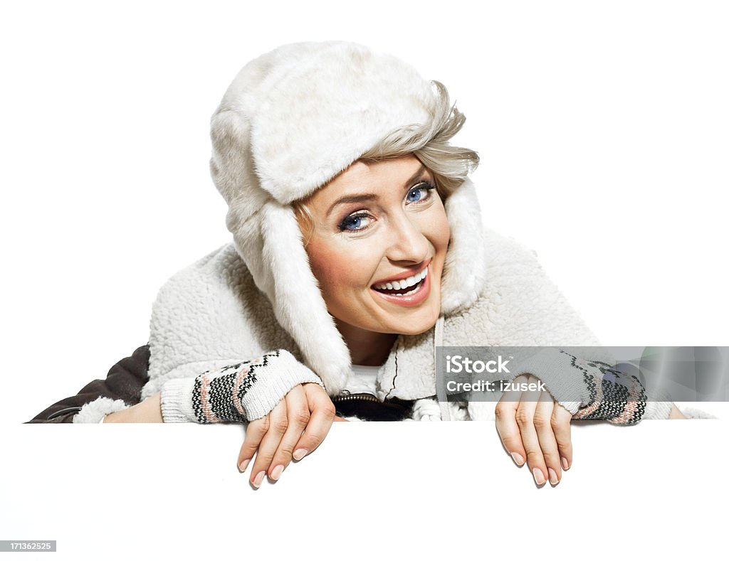 Winter Fashion Woman with Whiteboard A happy young woman wearing winter clothes holding a blank white board and smiling at the camera. Studio shot, white background. 20-29 Years Stock Photo