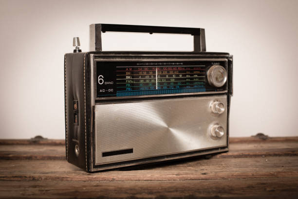 Vintage Black and Silver Portable Radio Sitting on Wood Table "Close up, slightly desaturated, color image of a vintage black and silver portable radio sitting on a wood table." vintage portable silver radio stock pictures, royalty-free photos & images