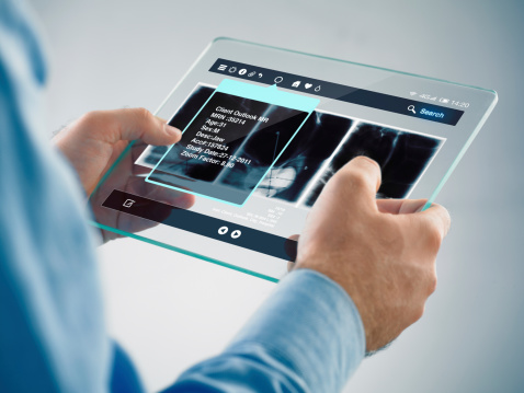 doctor holding a futuristic transparent digital tablet with x-ray displayed