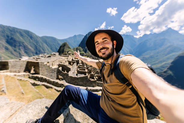 Happy young adult man taking selfie portrait in Machu Picchu Happy young adult man taking selfie portrait in Machu Picchu. Joyful traveler enjoying vacation visiting Peru. South american travel holidays concept. peru travel stock pictures, royalty-free photos & images