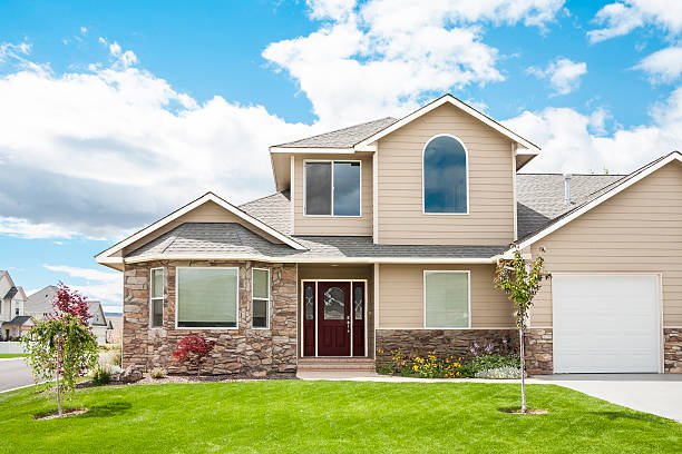 New home with green lawn, peaked roof; blue sky.