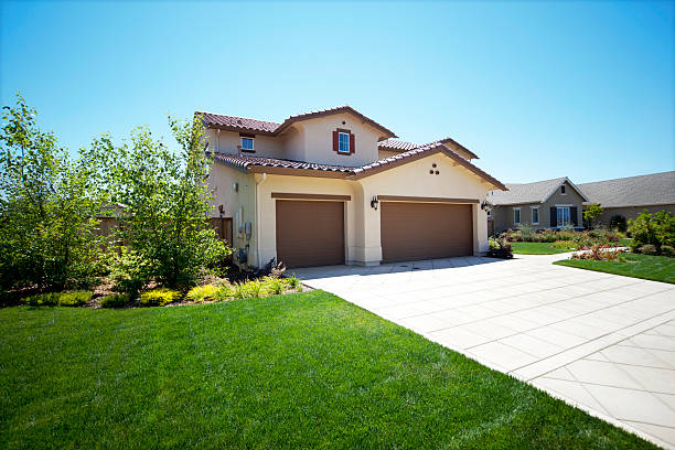 Front view of a new neat modern white low set single story family home with green grass and blue sky for copy space.