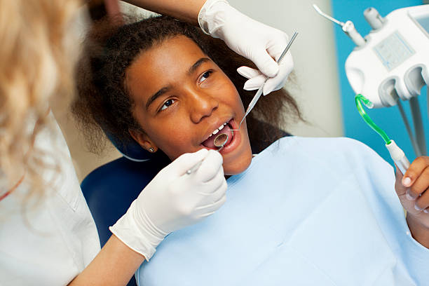 African Teenager Visit Dentist Office. Portrait of an cute african teenage girl sitting in a dentist chair at dentist office. Dentist is examining her teeth. dental drill stock pictures, royalty-free photos & images