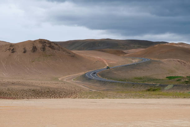 a mountain asphalt road leads to mountains in the volcanic zone in northern iceland. - journey camel travel desert imagens e fotografias de stock