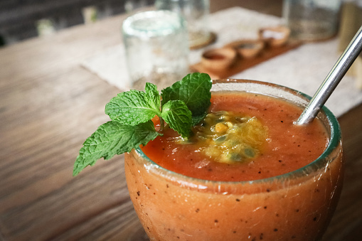 Papaya smoothie with passion fruit in glass on table in tropical cafe