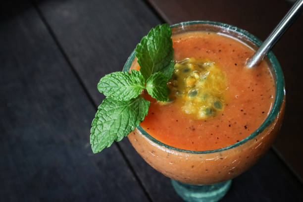 Papaya smoothie with passion fruit in glass on table in tropical cafe