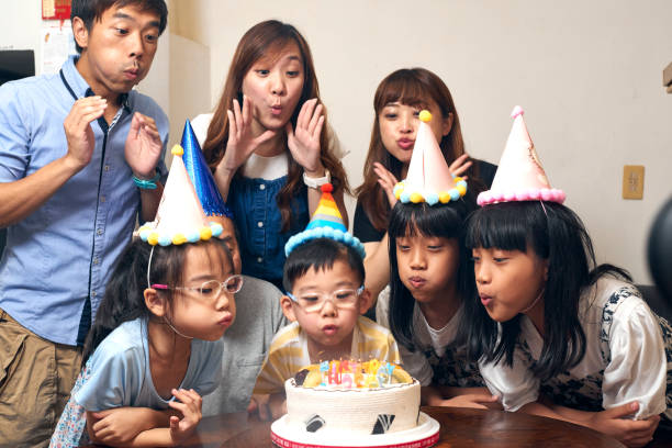 5歳の男の子が誕生日パーティーでろうそくを吹き消します。 - chinese ethnicity women 30s 35 40 years ストックフォトと画像