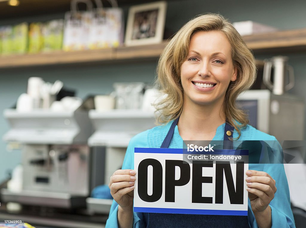 Femmina proprietario di un negozio con un'insegna aperto - Foto stock royalty-free di Adulto