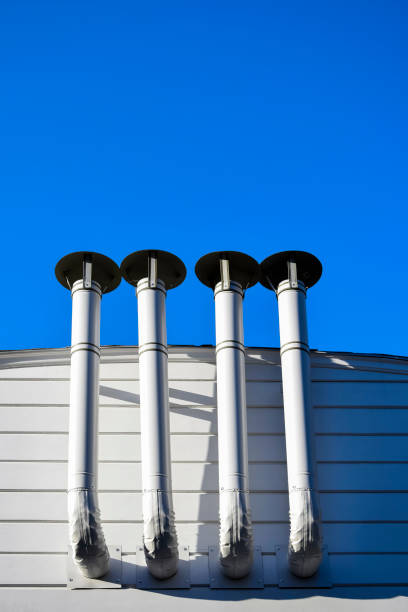 istock Ventilation pipes against blue sky. Building ventilation system. Fastening ventilation pipes to wall. Bottom view. Close-up. Selective focus. Copy space. 1713659430