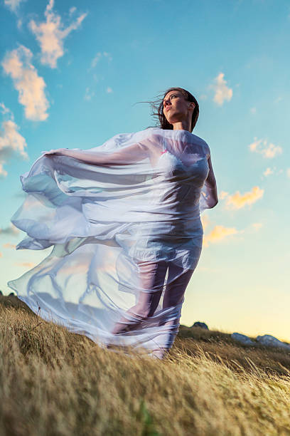 istock Young woman wrapped in white silk on hilltop 171366371