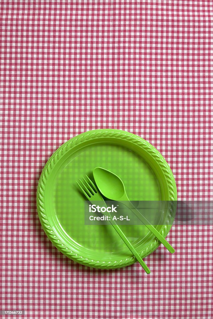 Picnic place setting "Picnic place setting with green plastic fork, spoon and plate on tablecloth" Backgrounds Stock Photo