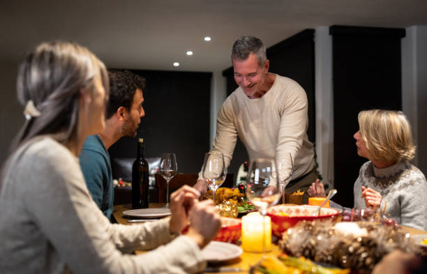 istock Man serving dinner while celebrating with his family on Christmas Eve 1713668649