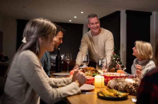 istock Happy man serving dinner while celebrating Christmas Eve with his family 1713668659
