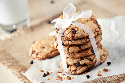 Homemade chocolate chip cookies tied white ribbon with milk on wooden table
