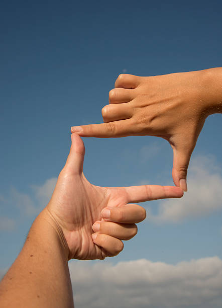 Hands making a frame in front of blue cloudy sky  Hand Frame determination focus the bigger picture human hand stock pictures, royalty-free photos & images