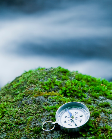compass on mossy rock near mountain stream