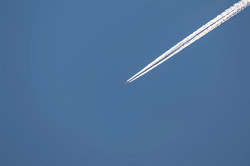 Plane flying through a clear blue sky leaving a long trail behind