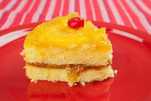 Serving of pineapple upside down cake on a red plate.