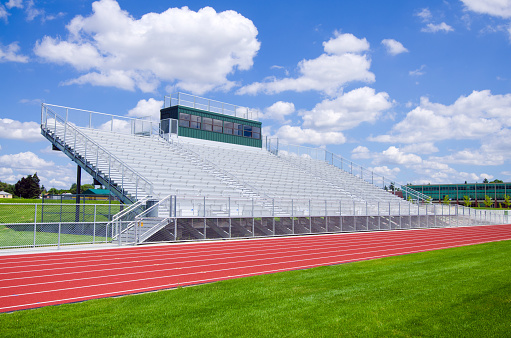 Bleachers at a high school football field with track.