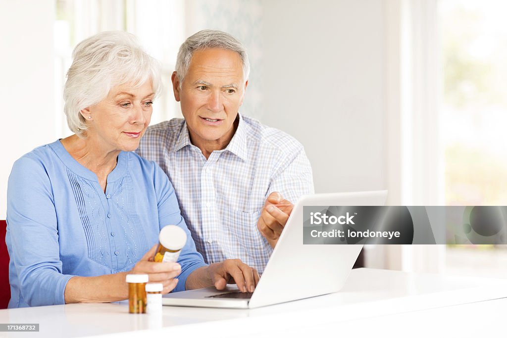 年配のカップルとピル本のノートパソコンのインターネットを閲覧します。 - ヘルスケアと医療のロイヤリティフリーストックフォト