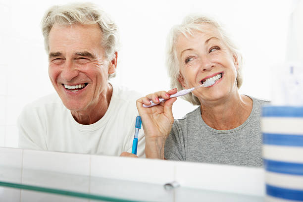 casal idoso em casa de banho lavar os dentes - brushing teeth women toothbrush brushing imagens e fotografias de stock