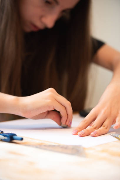 istock Teenage Girl at Home Sitting at Kitchen Table Working on Math Homework 1713688285