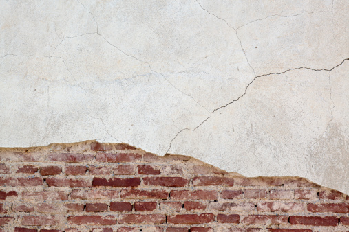An old brick wall with cracked stucco layer background