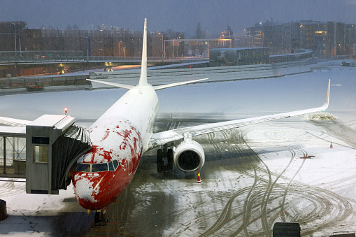 White passenger jetliner on the airport during a snow storm