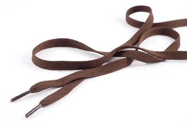 Brown shoe lace isolated on a white background. Main focus towards the foreground, softer focus towards the back.