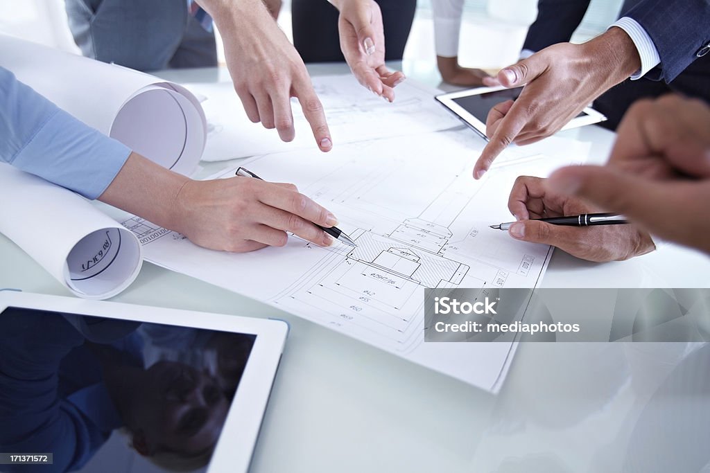 Scheme Colleagues discussing architectural plan at meeting Human Hand Stock Photo