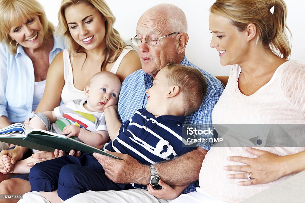 Rodzina siedzi na kanapie czytanie książki - Zbiór zdjęć royalty-free (Czytać)