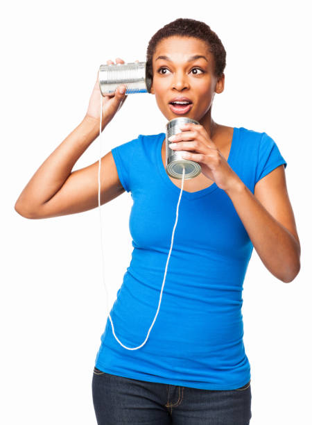 Curious African American woman holding a tin can phone. Vertical shot. Isolated on white.
