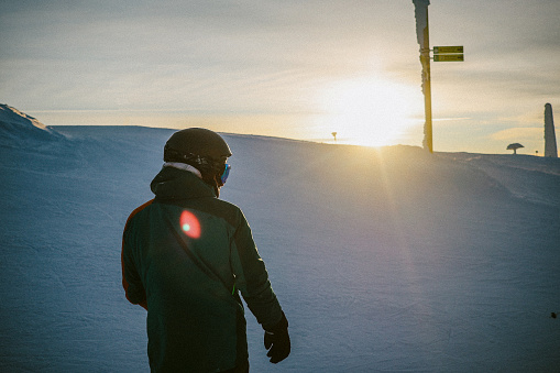 Male snowboarder riding in the sunset on a beautiful winter day.