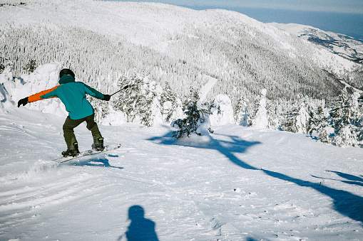 Male snowboarder riding on a beautiful winter day, filming with an action camera.