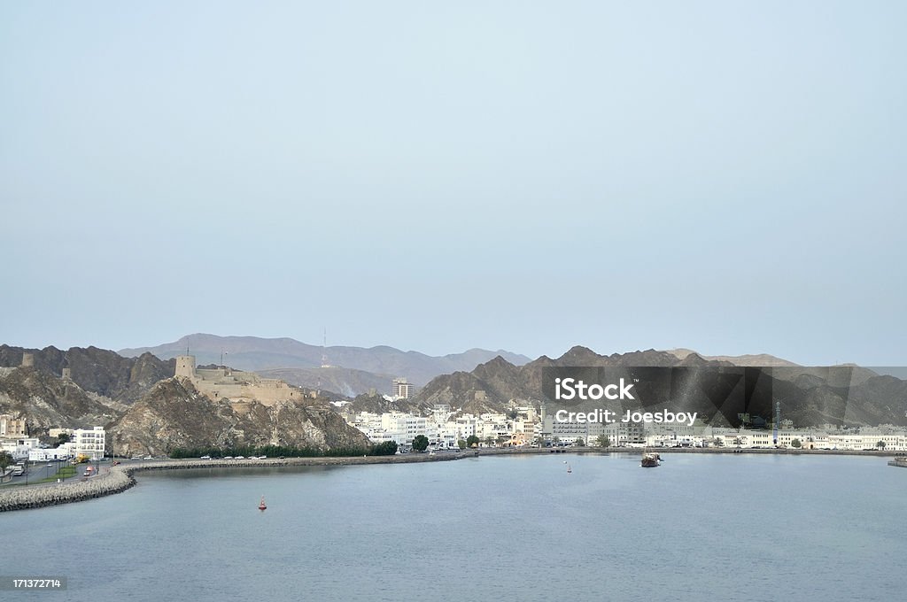 Muscat Governate In Port Sultan Qaboos With many names, Muscat, Muttrah, Muscat Governate, the small community nestles between the Arabian Sea and the Al Hajar Mountains in the background. Al Hajar Mountains Stock Photo
