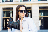 Stylish female model wearing sunglasses posing outdoor. Female fashion.
