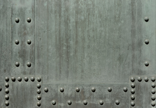 High resolution photograph of an old metal door with rivets.