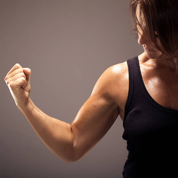 Square portrait of a beautiful and athletic woman pumping and showing her right bicep. Ideal for conveying any female fitness related concept.