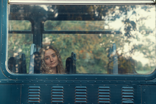 A blond woman looks through the window of a passanger train, Devon UK.