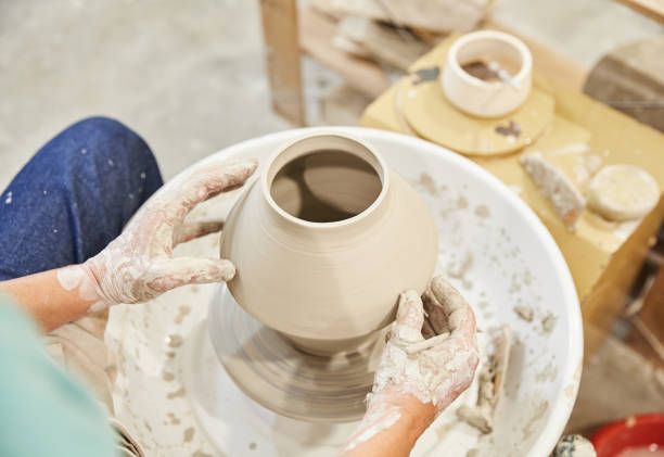 istock Unrecognizable woman sitting and crafting ceramic pot on pottery wheel 1713742453