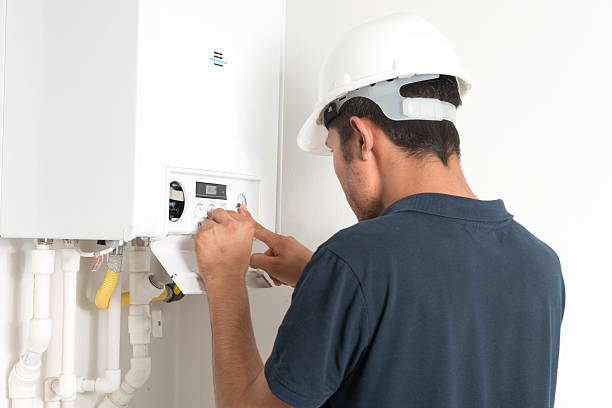 Male technician working in a boiler in a white room stock photo
