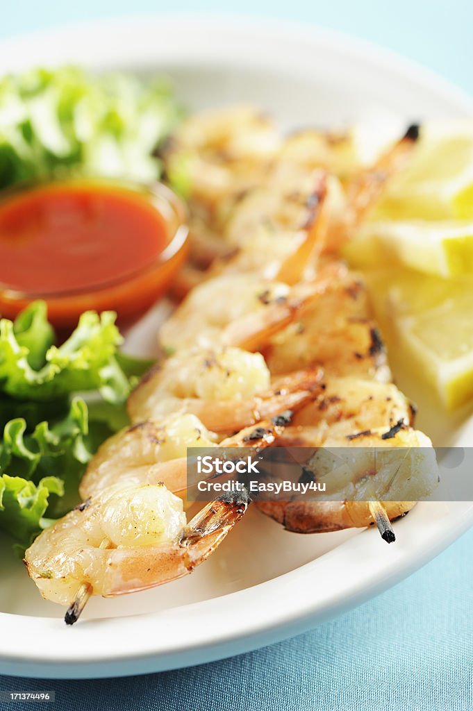 Shrimp kebabs "Grilled marinated shrimp kebabs with salad, sauce and lemon in a white plate, selective focus." Barbecue - Meal Stock Photo