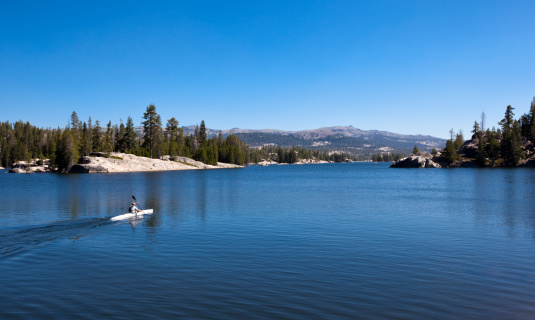A lone kayaker paddling on Utica Reservoir in the California Sierra Nevada.  Utica is a popular spot for camping and kayaking and is adjacent to Union and Spicer Reservoirs on the edge of the Carson Iceberg Wilderness.
