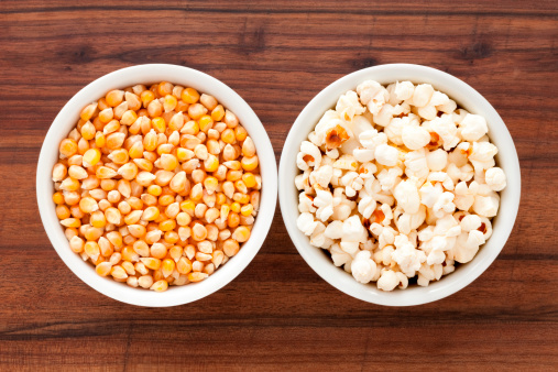 Top view of two bowls with corn grains and fresh popcorn for food processing concept